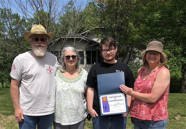 Quest first graduate with family and teacher 