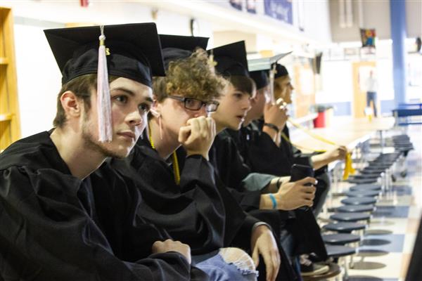 Seniors sitting in a row with cap and gowns